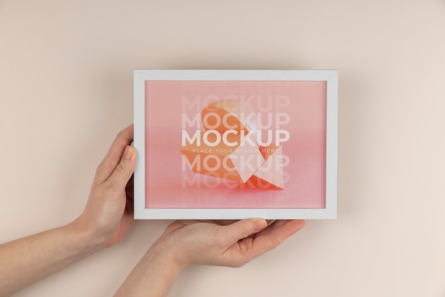 Hands holding white frame mockup top view