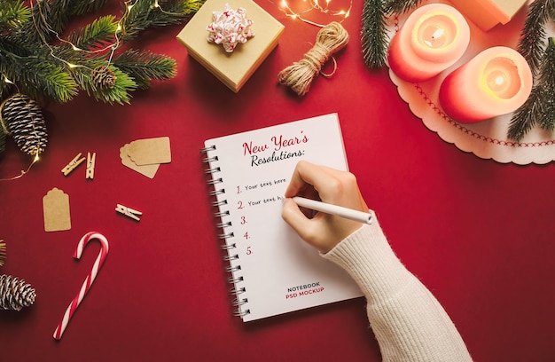 Handschrift in een notebookmodel met nieuwjaarsresolutie met kerstspullen op rode achtergrond