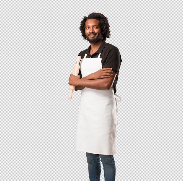 Красивый афро-американский пекарь, скрестив руки, улыбающийся и счастливый, уверенный в себе и дружелюбный
