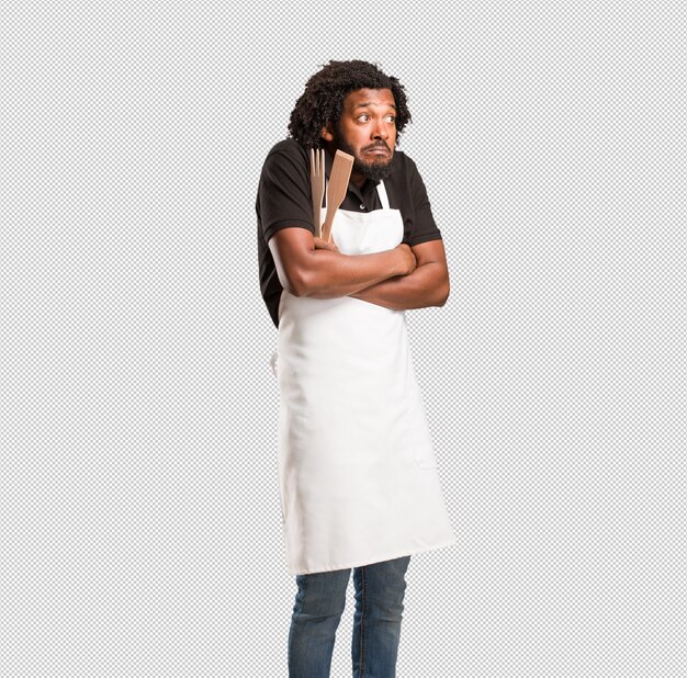 PSD handsome african american baker doubting and shrugging shoulders, concept of indecision and insecurity, uncertain about something