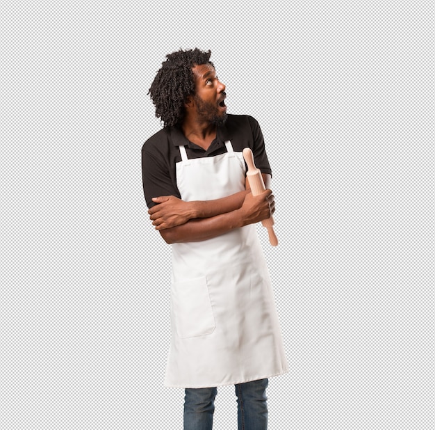 Красивый афро-американский пекарь, глядя вверх, думая о чем-то веселом и имея идею, концепцию воображения, счастливым и возбужденным