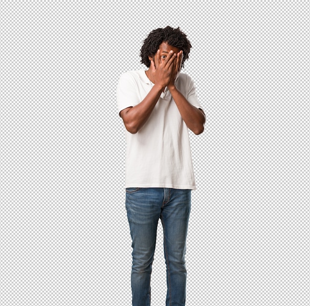 Handsome african american feels worried and scared, looking and covering face