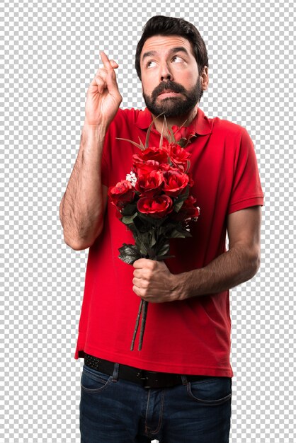 彼の指の交差点で花を持っているハンサムな男