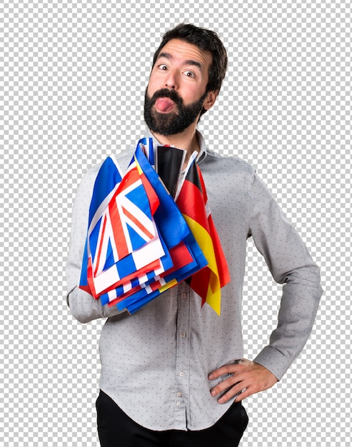 Handsome man with beard holding many flags and making a joke