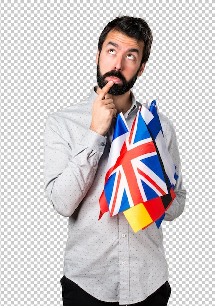 Bell'uomo con la barba che tiene molte bandiere e pensando