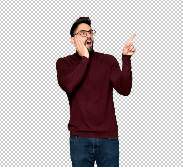 Handsome man with glasses pointing up and surprised