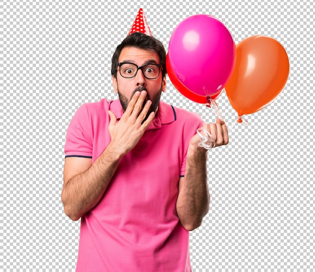 Красивый молодой человек держит воздушные шары и делает жест сюрприз