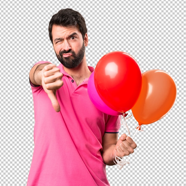 Handsome young man holding balloons and  making bad signal