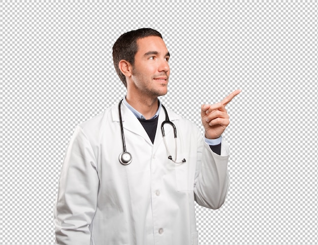 Happy doctor pointing against white background