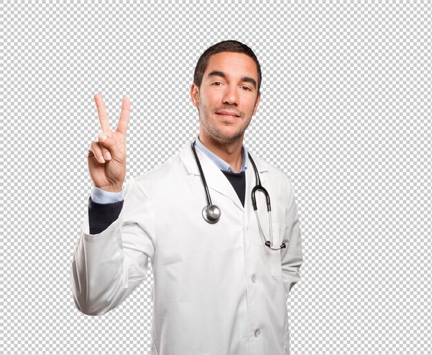 Happy doctor with a victory gesture against white background