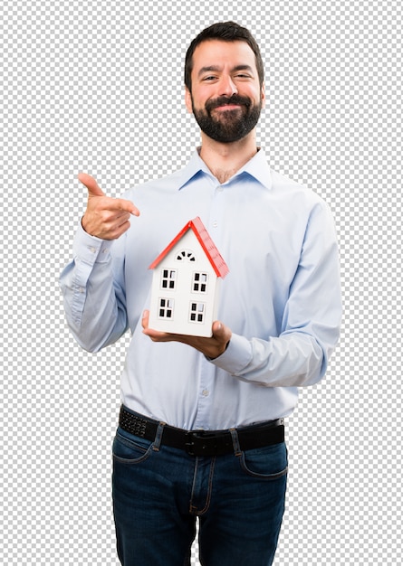 Happy handsome man with beard holding a little house