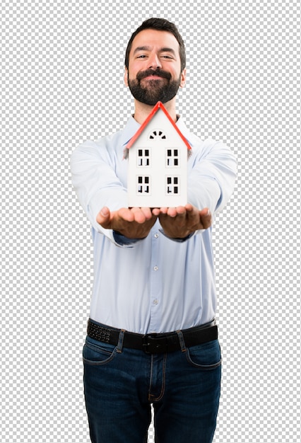 Happy handsome man with beard holding a little house