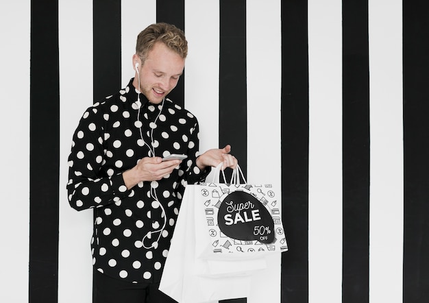 Happy man with shopping bags looking at mobile