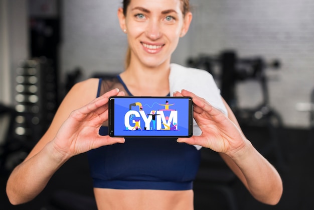 Happy sporty woman presenting smartphone mockup