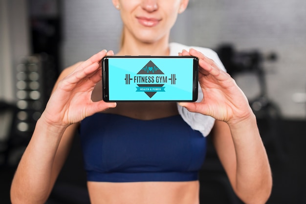 PSD happy sporty woman presenting smartphone mockup