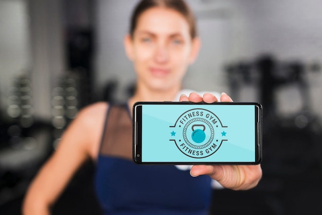 happy sporty woman presenting smartphone mockup