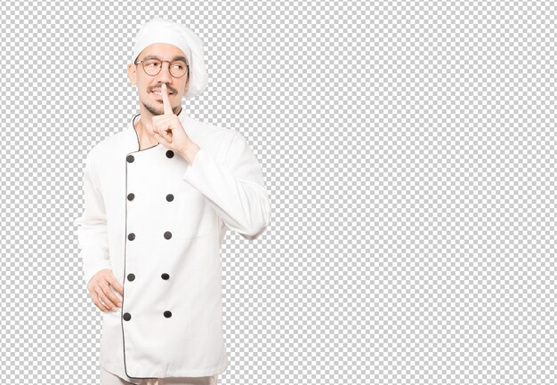 Happy young chef asking for silence gesturing with his finger