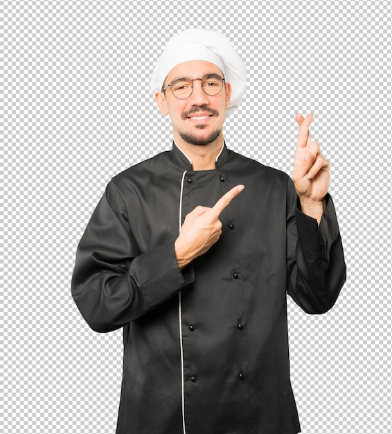 Happy young chef doing a crossed fingers gesture