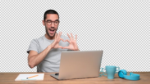 PSD happy young man doing a gesture of love sitting at his desk