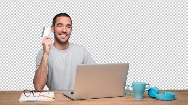 PSD happy young man sitting at his desk and holding a credit card