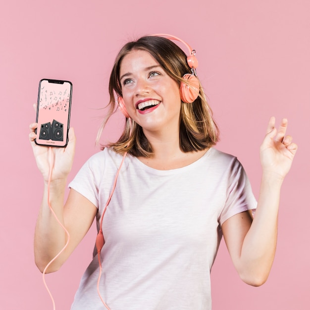 Happy young woman with headphones and cellphone mock-up