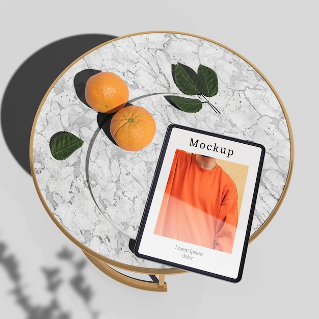 Высокий угол планшета на столе с апельсинами и листьями