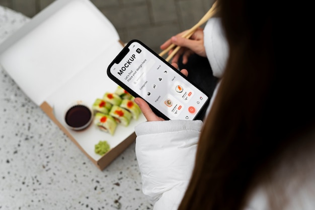 スマートフォンと寿司を持つハイアングルの女性