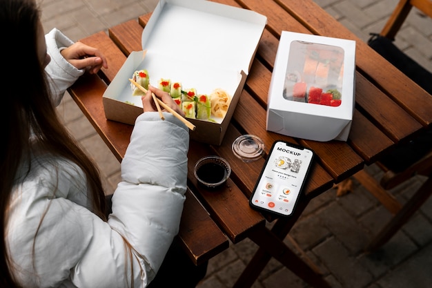 High angle woman with smartphone and sushi