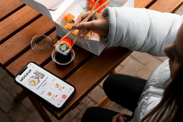 High angle woman with smartphone and sushi