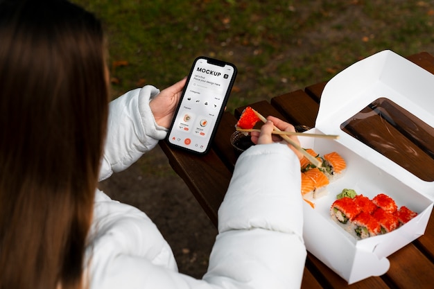 High angle woman with smartphone and sushi