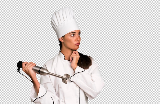 hispanic pretty young adult and expressive woman chef concept and hand blender