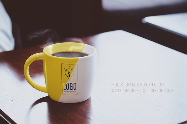 PSD hot black coffee cup on wood table top at coffee shop mockup