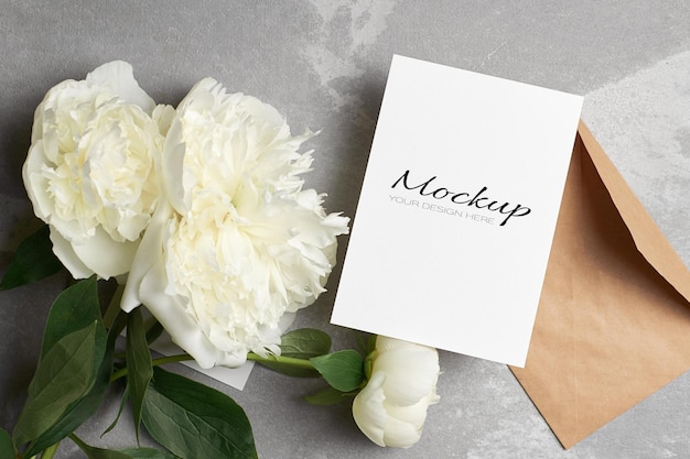 封筒と灰色の白い牡丹の花と招待状またはグリーティングカードのモックアップ