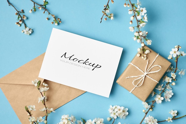 Invitation or greeting card mockup with gift box, envelope and cherry tree blooming twigs