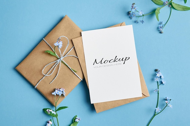 Invitation or greeting card mockup with gift and spring forget-me-not flowers on blue