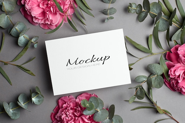 Invitation or greeting card mockup with peony flowers and eucalyptus twigs on grey