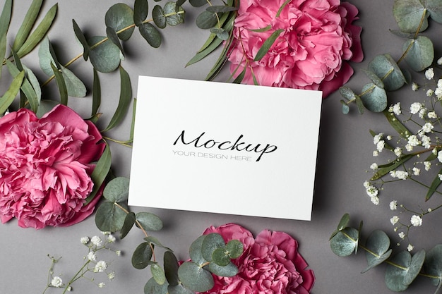 Invitation or greeting card mockup with peony flowers, hypsophila and eucalyptus twigs