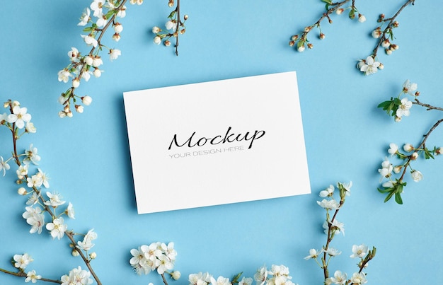 Invitation or greeting card mockup with spring cherry blossom flowers twigs on blue