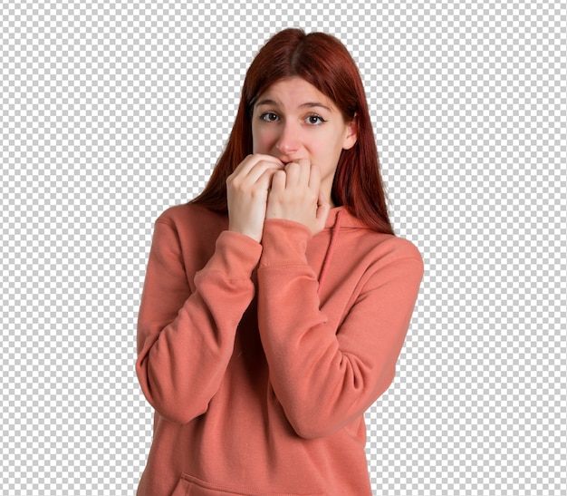 Jong roodharig meisje met roze sweatshirt is een beetje nerveus en bang om handen naar de mond te brengen