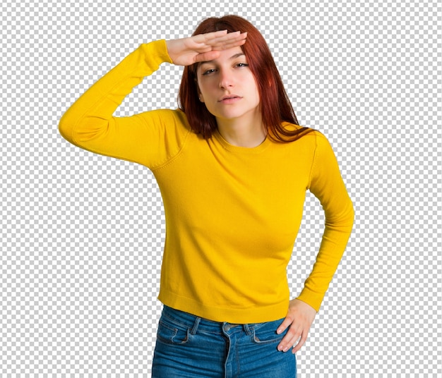 Jong roodharigemeisje die met gele sweater ver weg met hand kijken om iets te kijken