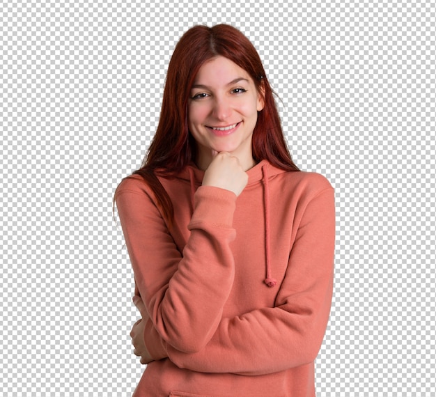 Jong roodharigemeisje met roze sweatshirt die en aan de voorzijde met zeker gezicht glimlachen kijken
