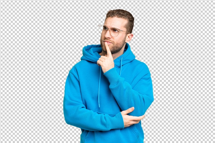 PSD jonge knappe blonde man over geïsoleerde chroma sleutel achtergrond met twijfels terwijl hij omhoog kijkt