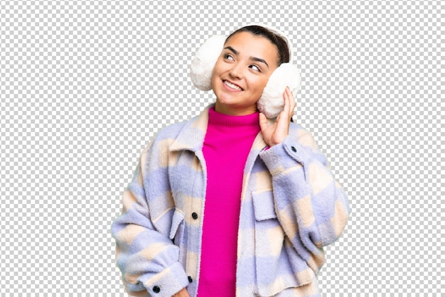 Jonge vrouw die wintermuffen draagt over een geïsoleerde chroma sleutel achtergrond die aan een idee denkt
