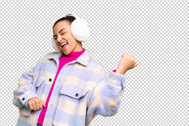 Jonge vrouw met wintermuffen op een geïsoleerde chroma-sleutel achtergrond die een gitaargeste maakt