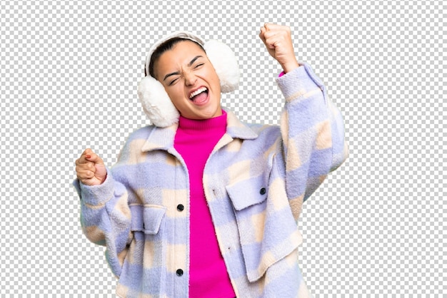 Jonge vrouw met wintermuffen op een geïsoleerde chroma sleutel achtergrond viert een overwinning