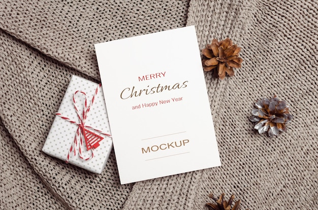 Kerst of nieuwjaar wenskaart mockup met geschenkdoos en kegels decoraties op gebreide achtergrond