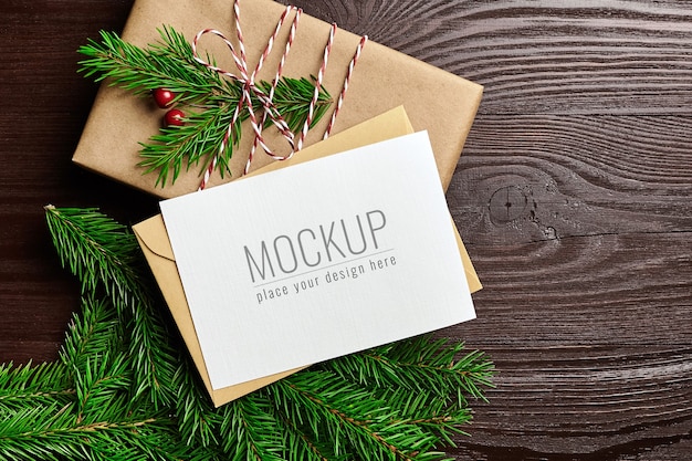 Kerst wenskaart mockup met geschenkdoos en fir tree takken op houten achtergrond