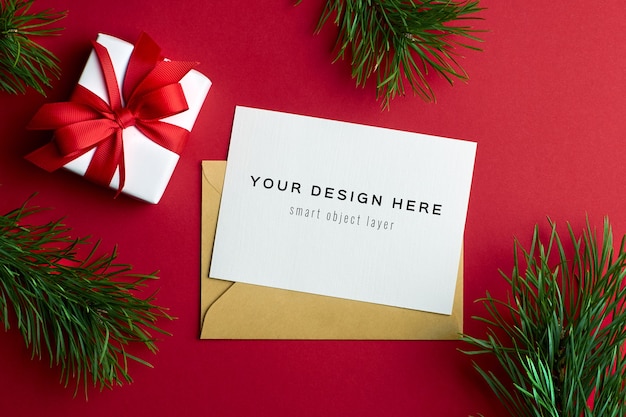 Kerst wenskaart mockup met geschenkdoos en pijnboomtakken op rood