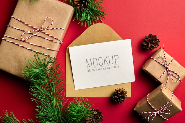 Kerst wenskaart mockup met geschenkdozen en pijnboomtakken en kegels op rood