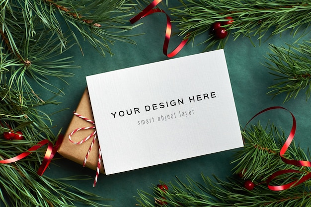 Kerst wenskaart mockup met versierde geschenkdoos en pijnboomtakken op groen